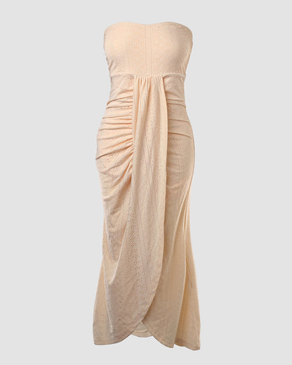 Sleeveless ruched vacation dress with a cinched waist, a draped bandeau-style bodice, eyelet embroidery, a slit, and an asymmetrical hem